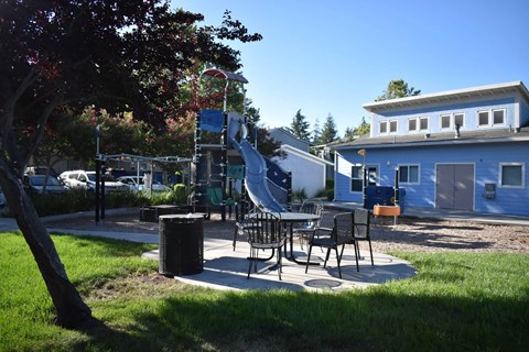A playground with a slide and a picnic table.