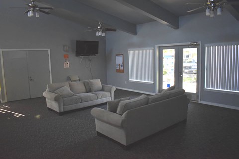 A living room with a grey couch and a television on the wall.