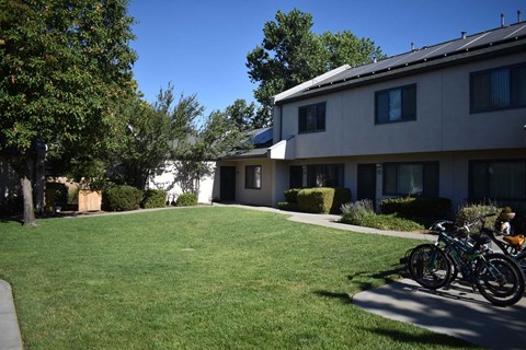 A bicycle is parked on the grass in front of a building.