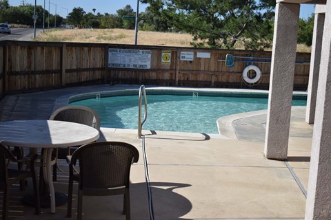 A pool with a table and chairs in front of it.