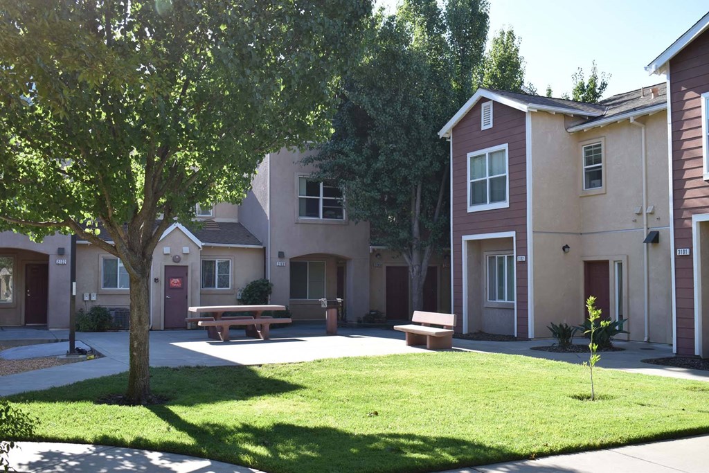a yard with a picnic table in front of some apartments