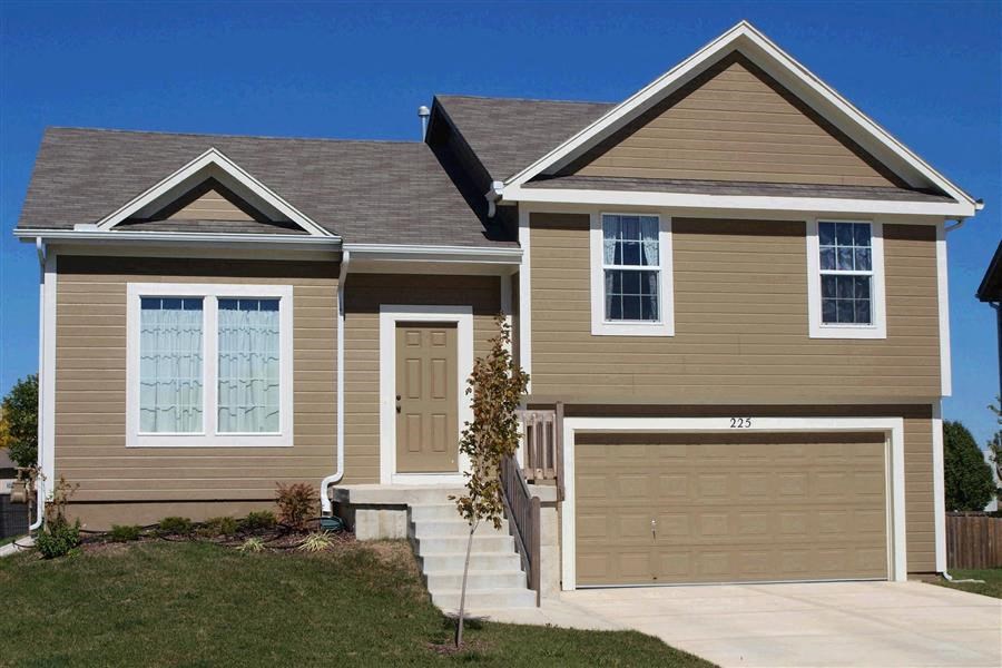 a tan house with a garage door and a driveway