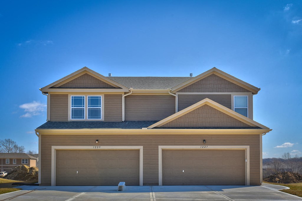 a tan house with two garage doors