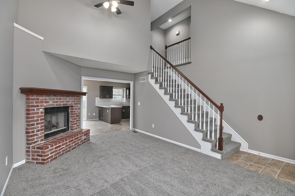 A living room with a fireplace and a staircase.