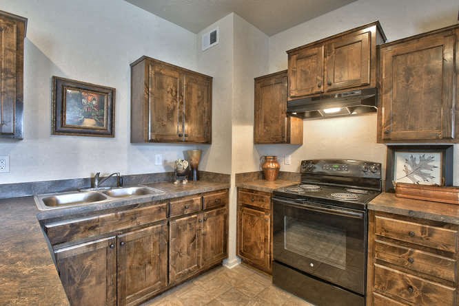 a kitchen with wooden cabinets and a stove and a sink