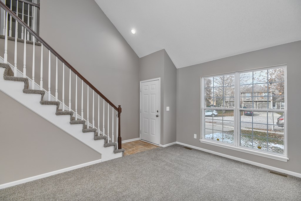 A room with a staircase and a door leading to a balcony.
