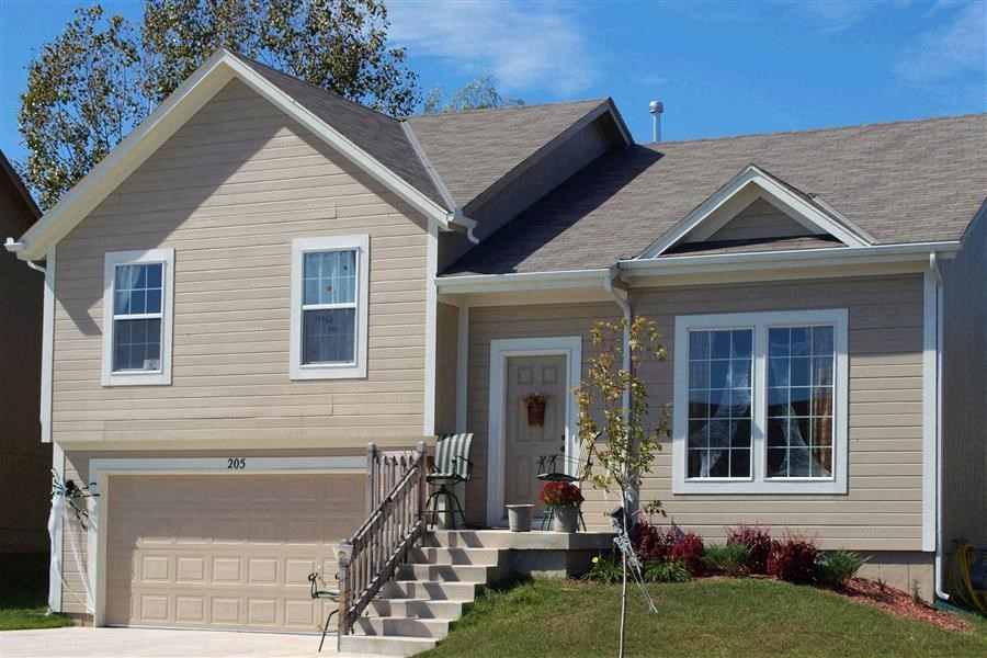 a tan house with a front porch and a garage door