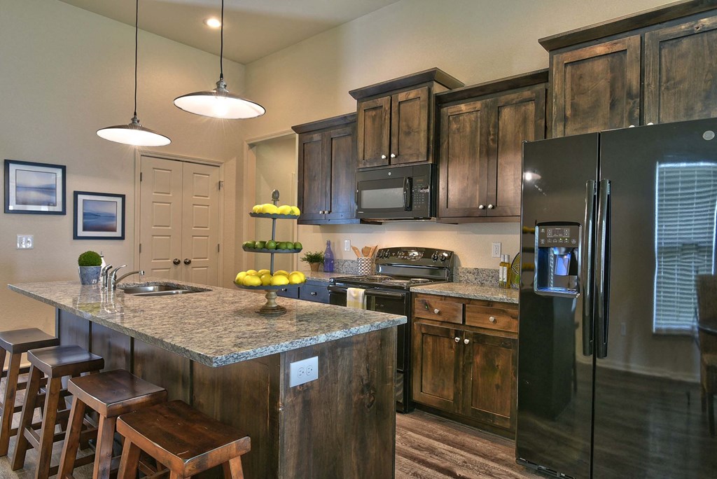 A kitchen with granite countertops and wooden cabinets.