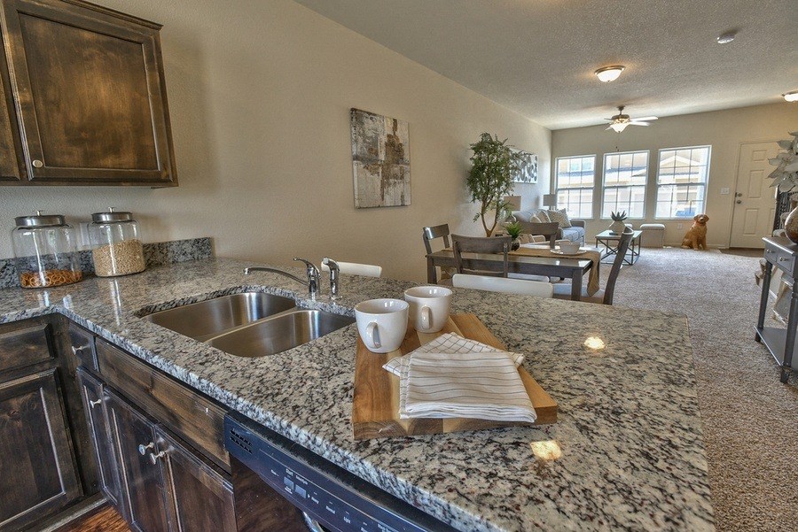 the view of the kitchen and living room from the counter top of a granite counter