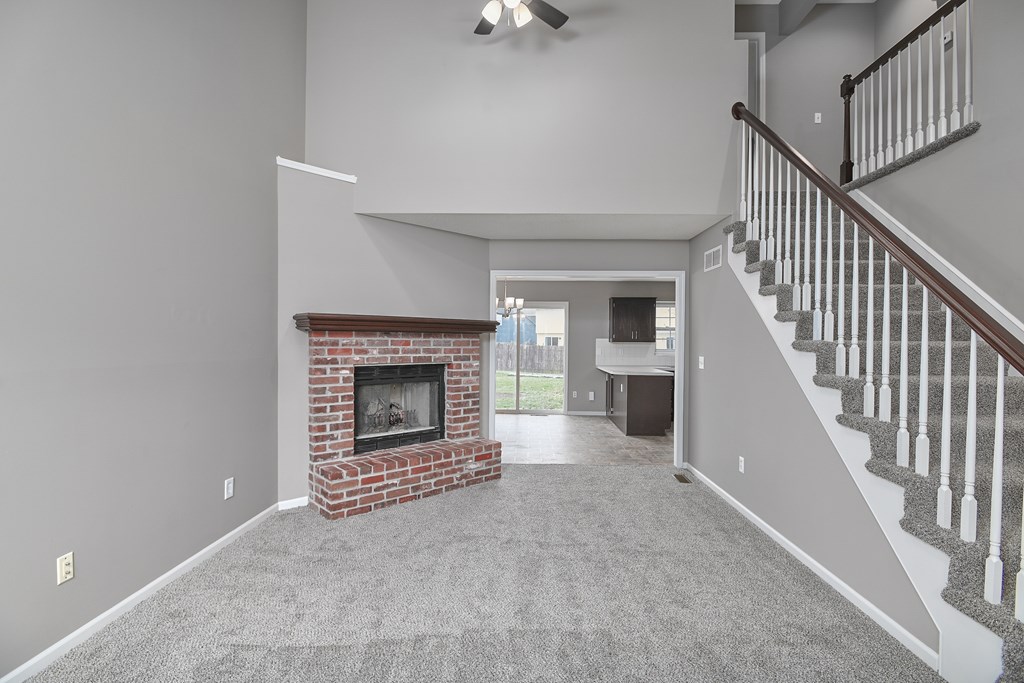 A living room with a fireplace and a staircase.