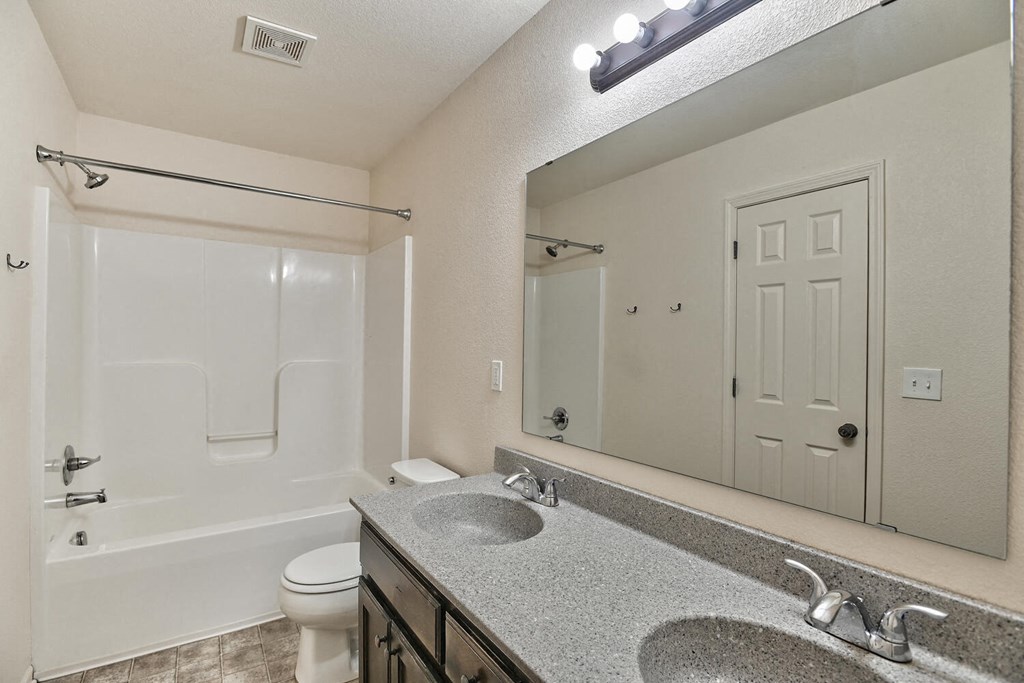 a bathroom with a large mirror and a sink and a toilet