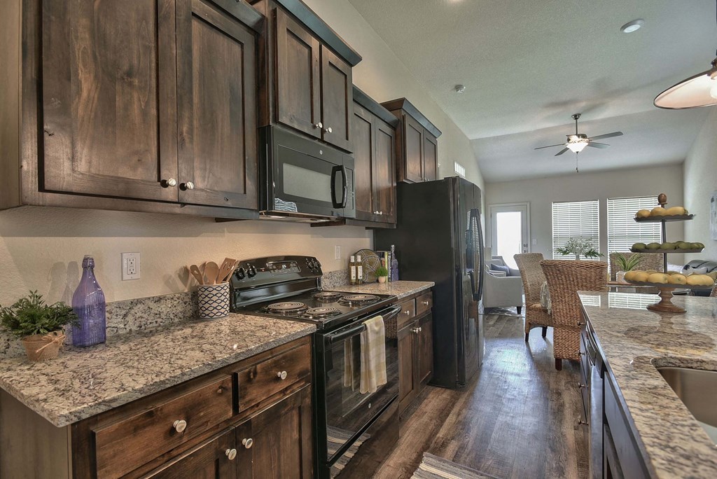 A kitchen with wooden cabinets and a black refrigerator.