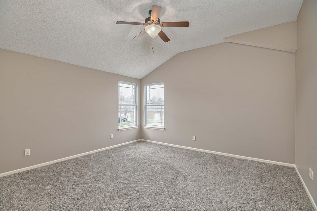 an empty living room with a ceiling fan and a window