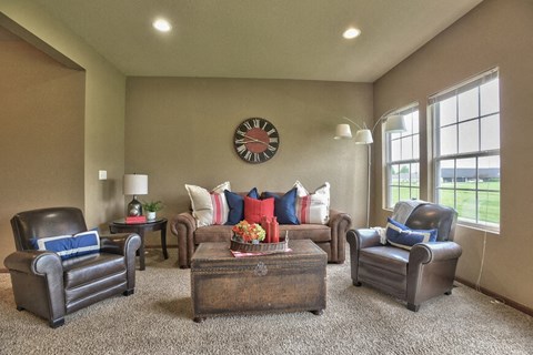 a living room with couches and chairs and a clock on the wall