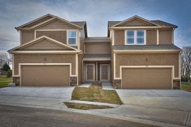 a brown house with two garage doors