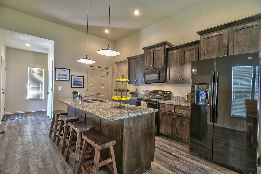 A kitchen with a black refrigerator and wooden cabinets.