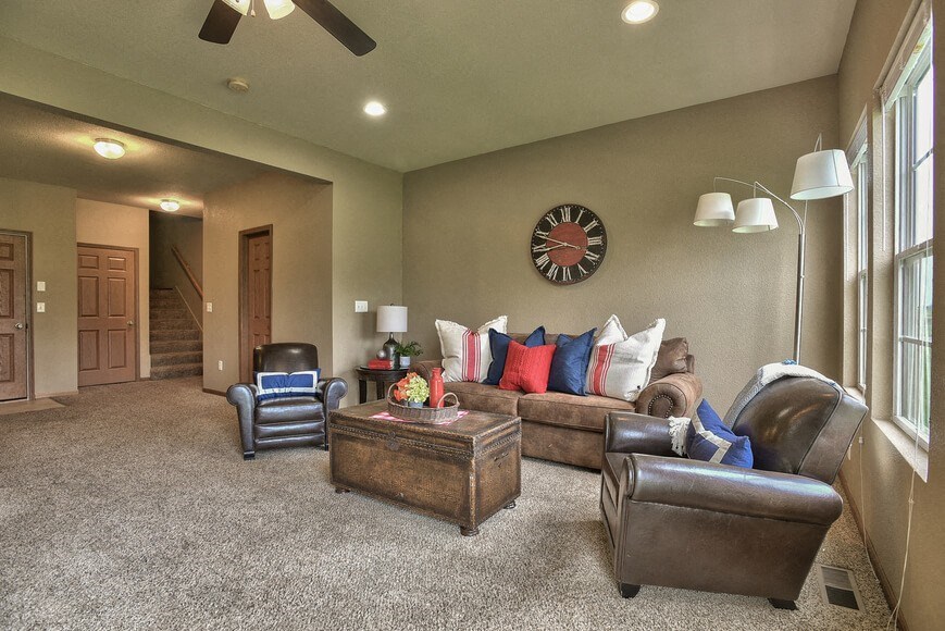 a living room with couches and chairs and a clock on the wall
