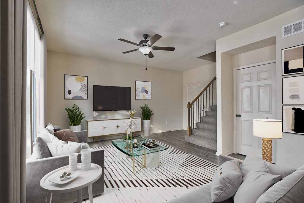 an open living room with a ceiling fan and a staircase