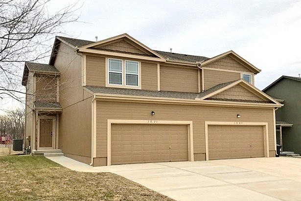 a brown house with two garage doors and a driveway