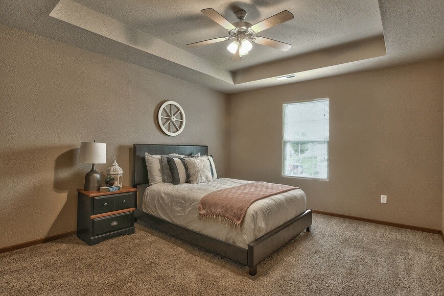 an empty bedroom with a bed and a ceiling fan