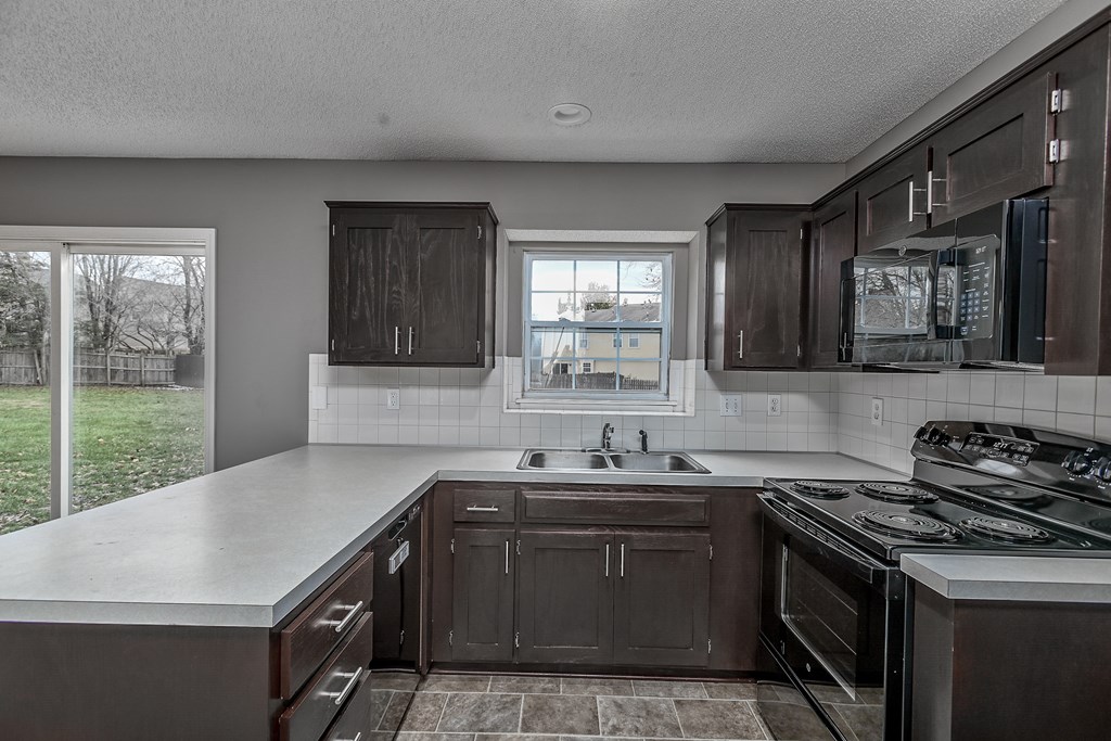 A kitchen with dark brown cabinets and a white countertop.