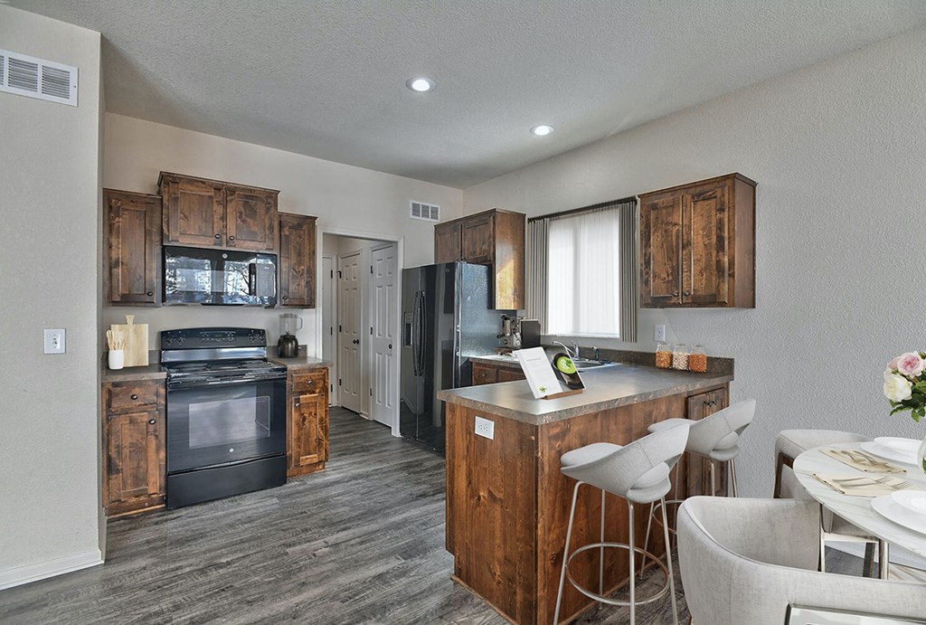 a kitchen with wooden cabinets and appliances and a table and chairs
