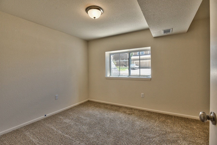 an empty bedroom with a window and a carpeted floor