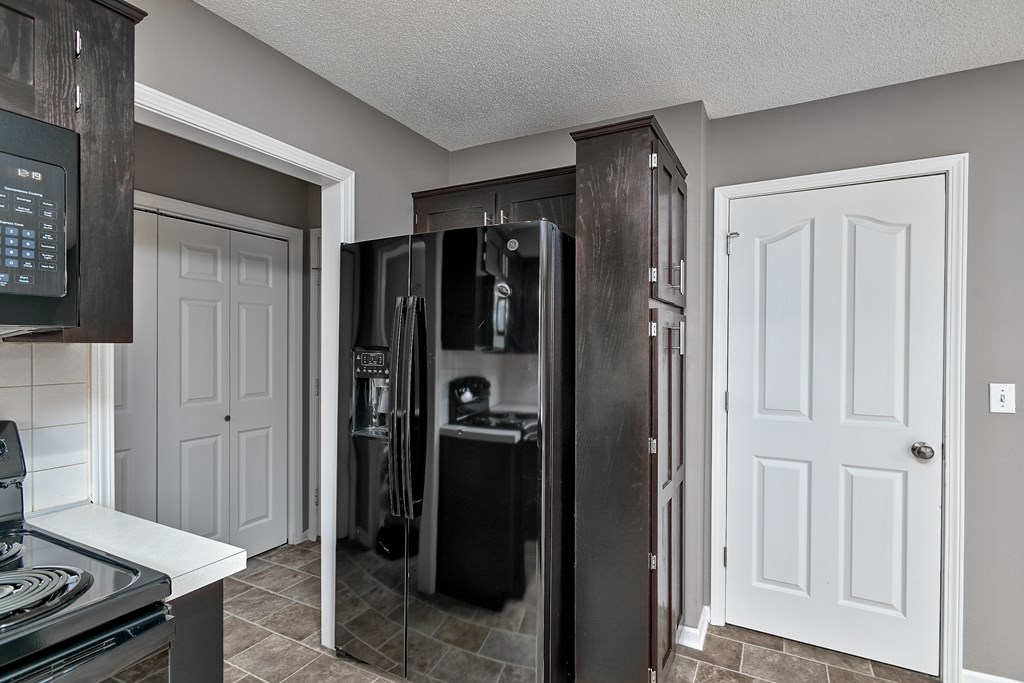 A kitchen with a refrigerator, oven, and microwave.