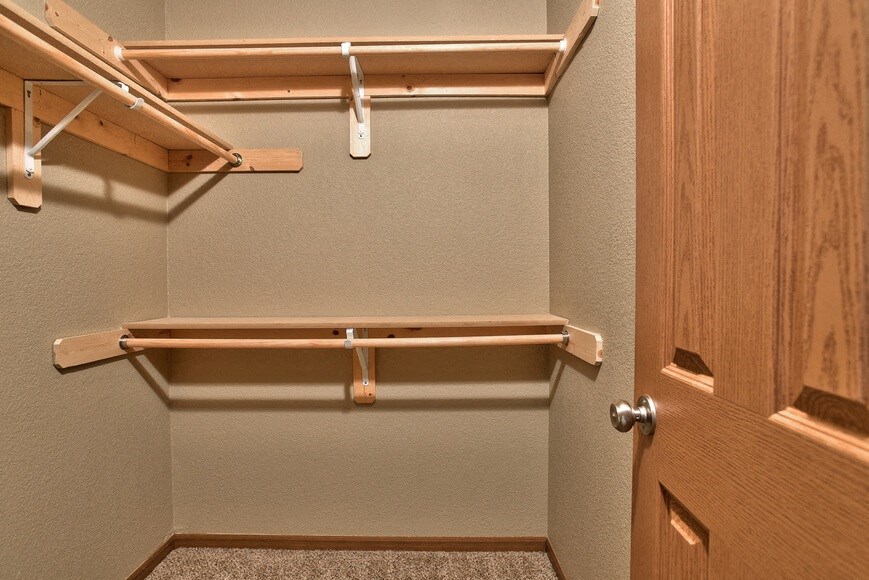 a walk in closet with a wooden shelf and a door