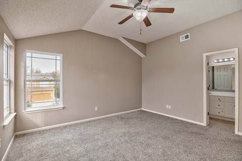 an empty bedroom with a ceiling fan and a window