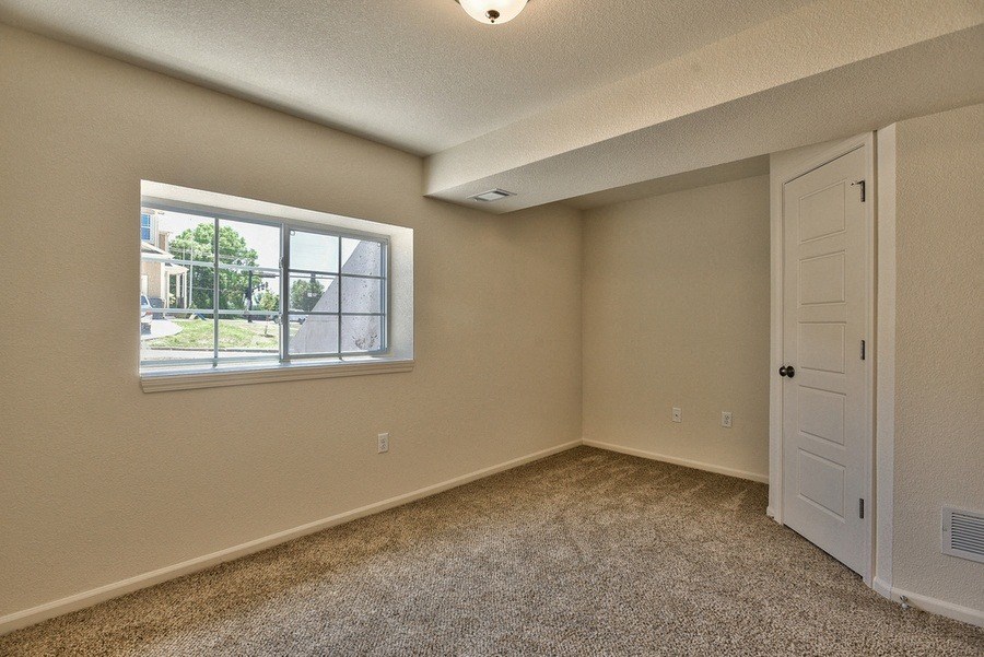 an empty bedroom with a window and a door