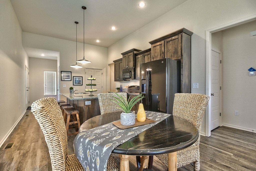 A modern dining room with a black table and wicker chairs.