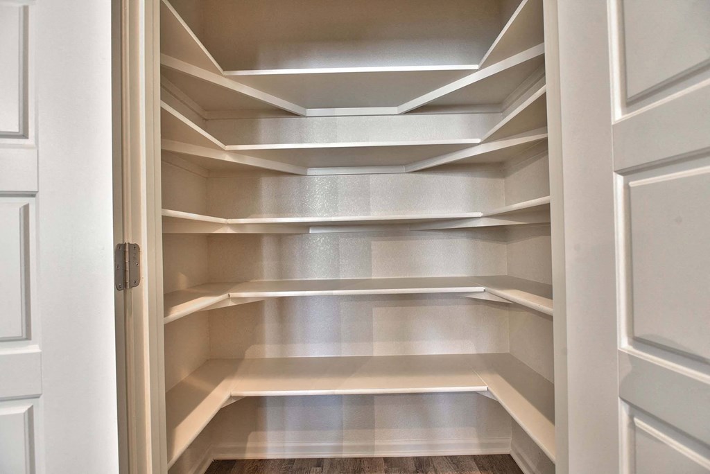 a walk in closet with white shelves and a door