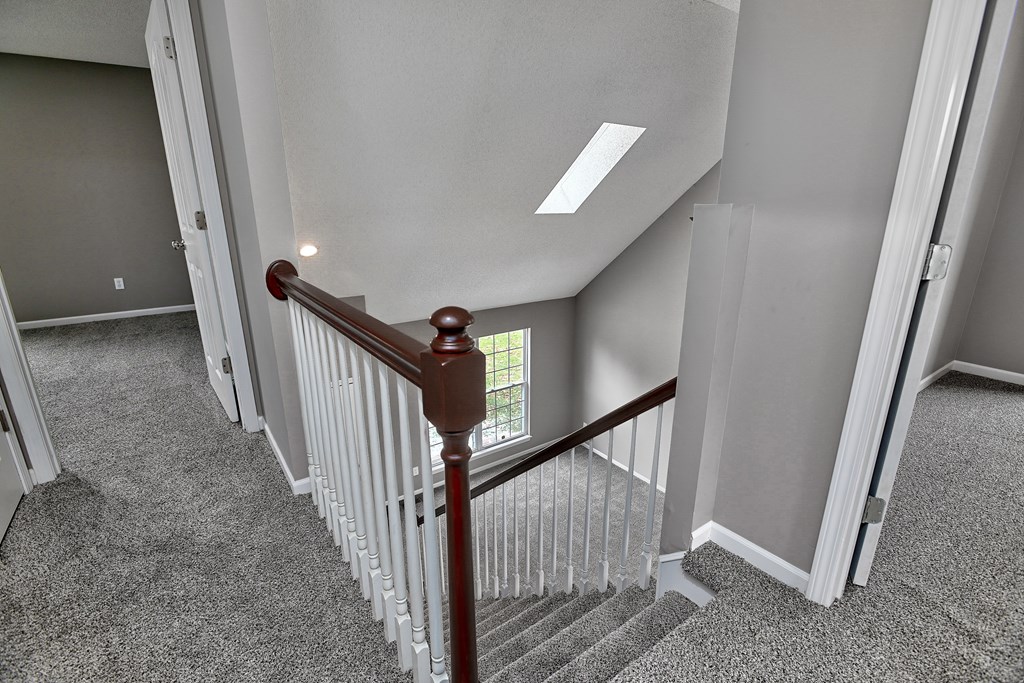 A staircase with a red handrail and white balusters.