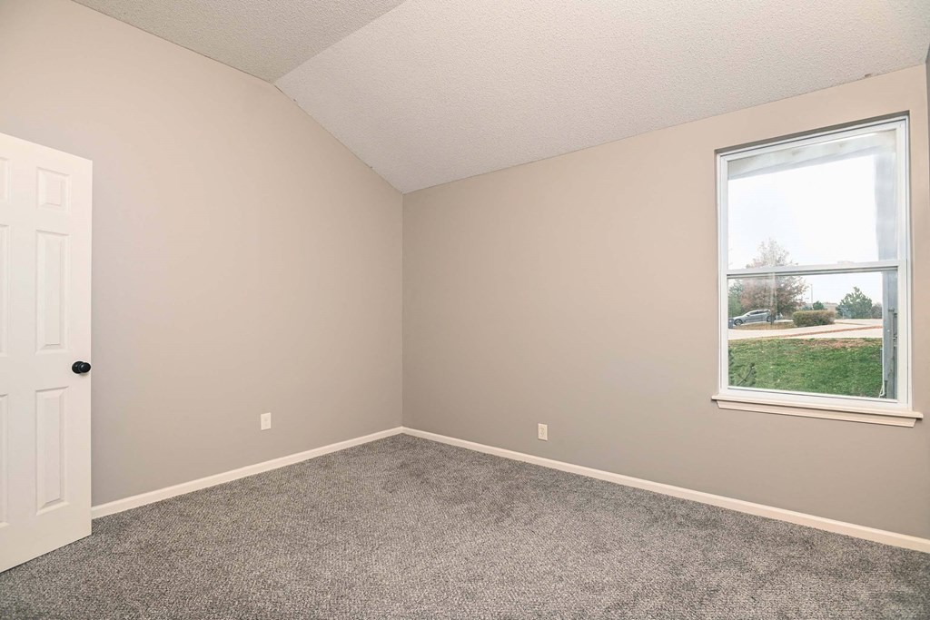 an empty bedroom with a window and carpet
