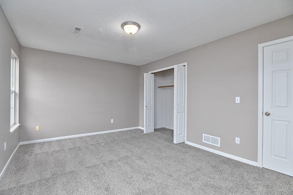 A room with a carpeted floor and a doorway leading to another room.