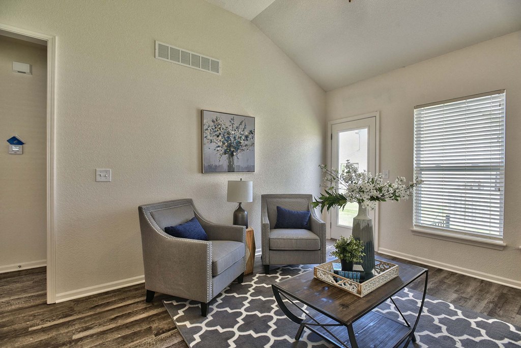 A living room with two chairs, a coffee table, and a painting on the wall.