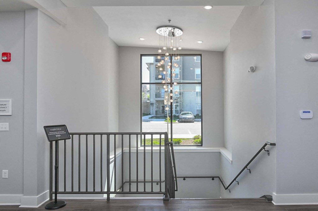 the landing at the top of the stairs has a chandelier and a window