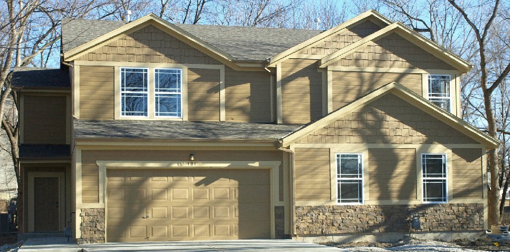 a tan house with a garage door and a stone facade