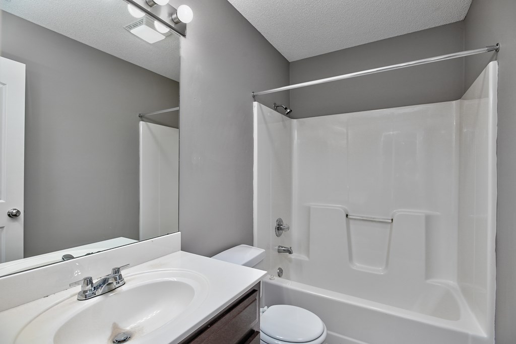 A white bathroom with a toilet, sink, and shower.
