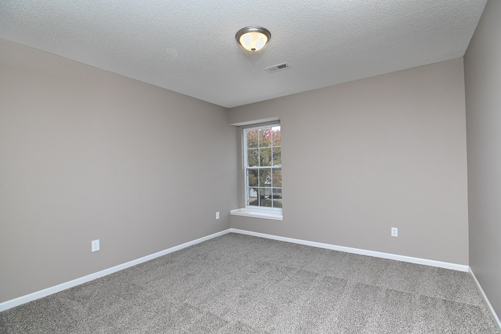 A room with a carpeted floor and a window.
