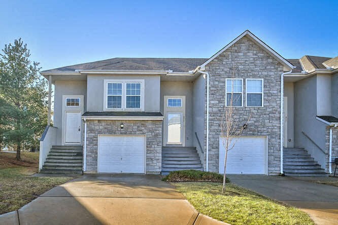 a brick house with two garage doors and stairs