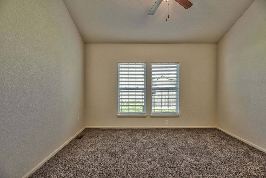 A room with a ceiling fan and carpeted floor.