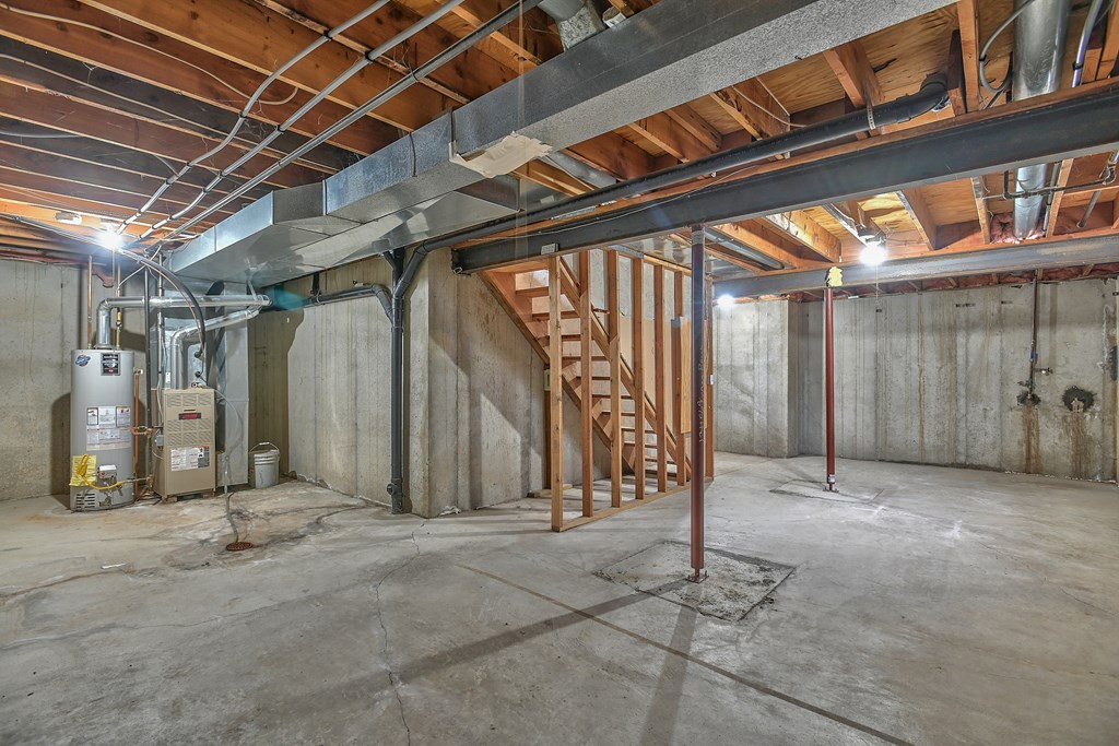 A large empty room with a staircase under a wooden ceiling.
