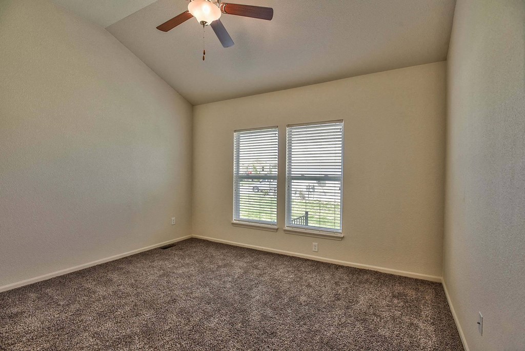 an empty living room with a ceiling fan and a window