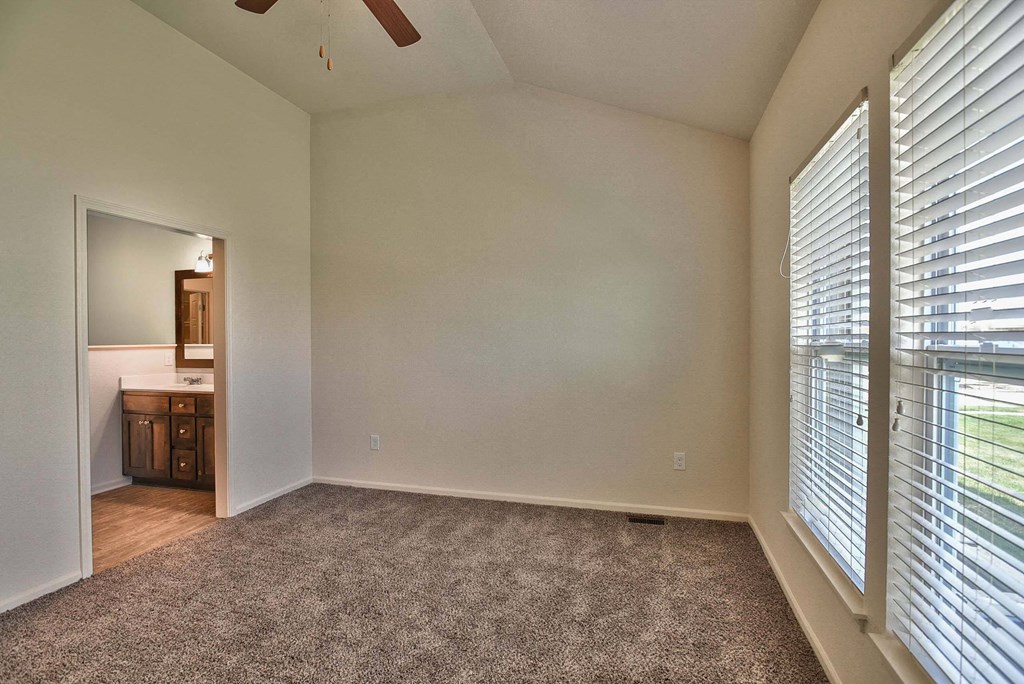 A room with a carpeted floor and a ceiling fan.