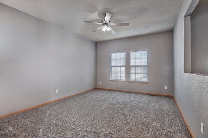 an empty room with a ceiling fan and a window