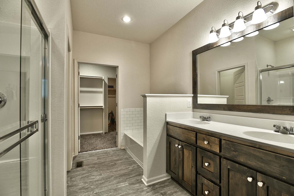A bathroom with a sink, mirror, and a walk-in shower.