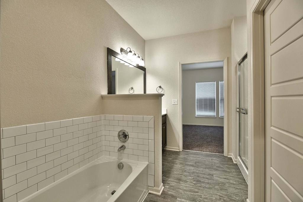 a bathroom with a tub and a hallway with a door