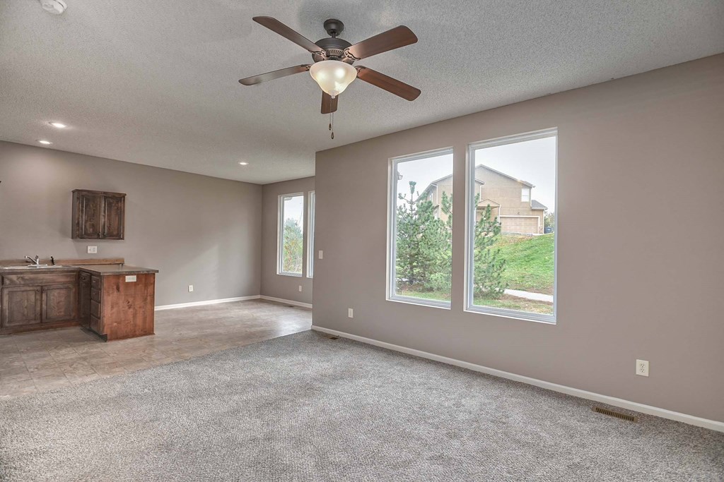 an empty living room with a ceiling fan and a window
